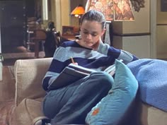 a woman sitting on a couch reading a book