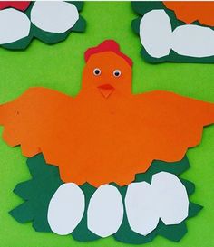 an orange and white paper cut out of the shape of a chicken sitting on top of green leaves