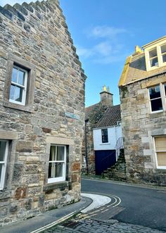 an old stone building on the side of a road with two windows and one door