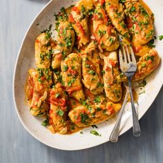 a white plate topped with chicken covered in sauce and garnished with parsley