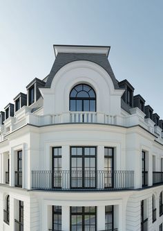 a large white building with lots of windows and balconies on the top floor