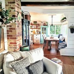 a living room filled with furniture next to a kitchen and dining room table in front of a brick wall