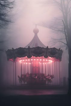 a merry go round in the fog with lights on it's sides and trees