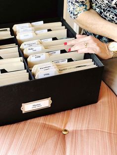 a woman holding her hand out in front of a drawer full of file folders