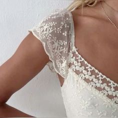 the back of a woman's wedding dress with white flowers on it and lace detailing