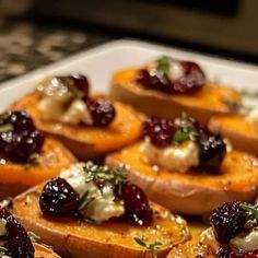 a white plate topped with sweet potatoes covered in cheese and cranberry toppings