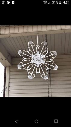 a white chandelier hanging from the side of a house in front of a window