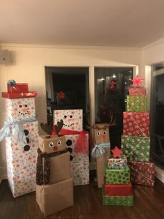 christmas presents are stacked on top of each other in front of the window and decorated with reindeer faces