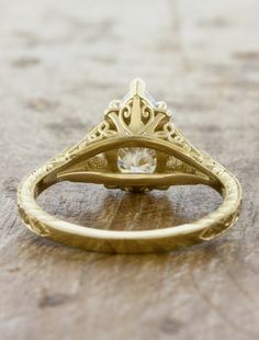 a gold ring with a diamond in the center on a wooden surface, close up