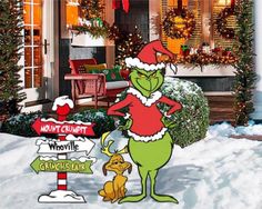 the grinch is standing next to a christmas sign