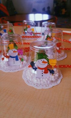 there are many small glass cups with snowmen in them on top of a table