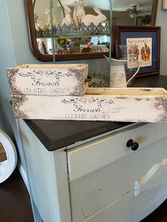 two wooden signs sitting on top of a dresser next to a mirror and other items