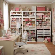 a room filled with lots of pink and white storage containers next to a desk in front of a window