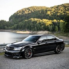 a black car parked on the side of a road next to a body of water