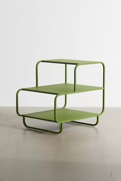 two tiered green shelfs sitting on top of a cement floor in front of a white wall