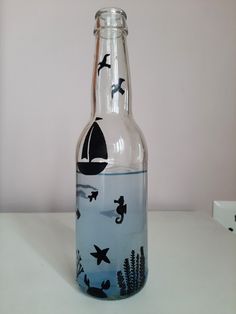 a glass bottle with birds painted on the bottom is sitting on a white countertop