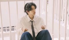 a young man wearing headphones sitting on the ground in front of a stair railing