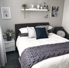 a bedroom with grey walls and white bedding, potted plants on the wall