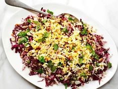 a white plate topped with rice and veggies on top of a marble table