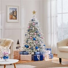 a white christmas tree with blue and pink ornaments in a living room decorated for christmas