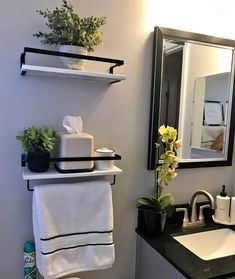 a white toilet sitting next to a bathroom sink under a mirror and shelf above it