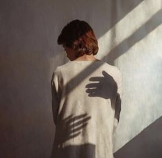 a woman standing in front of a wall with her hand on the back of her body