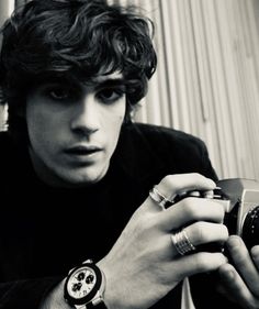 a young man holding a camera and looking at it