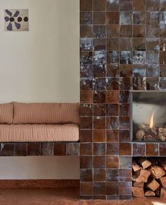 a living room with a fire place next to a brick wall and wood logs on the floor