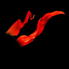 a red scarf blowing in the wind on a black background