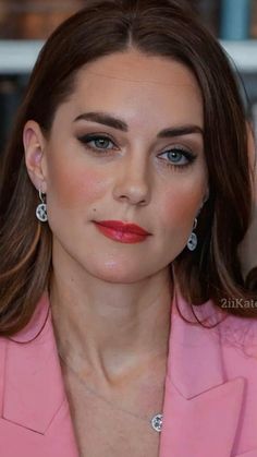 a woman with brown hair wearing a pink suit and diamond earring set on her left ear