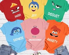 an assortment of t - shirts with cartoon characters on them, all in different colors