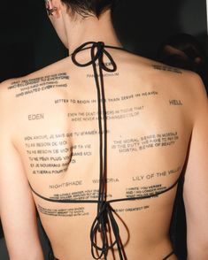 the back of a woman's body with words on it and writing all over her chest