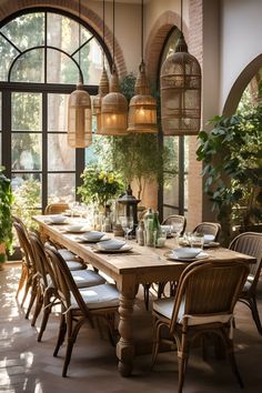 a dining room table set with place settings and hanging plants in the window sill