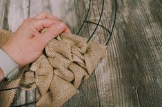 a hand is holding a piece of burlock on top of a wooden table