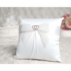 a white pillow with a bow and diamond brooch on the front is sitting on a table