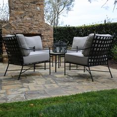 two chairs and a table sitting on top of a stone patio