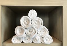 a pile of white towels sitting on top of a wooden shelf