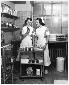 two women in aprons are standing near a table with pots and pans on it