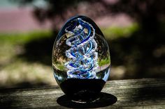 a glass vase sitting on top of a wooden table next to a tree in the background