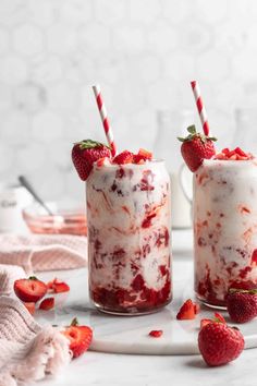 two glasses filled with strawberries on top of a white table next to each other