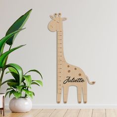 a wooden giraffe height chart next to a potted plant