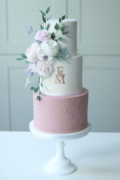 a white and pink wedding cake with flowers on top