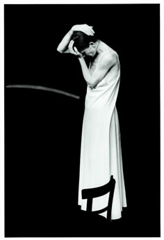 a black and white photo of a woman in a long dress sitting on a chair