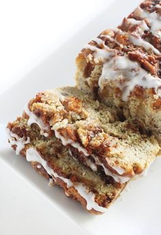 two slices of cinnamon roll with icing sitting on a white plate next to each other