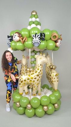 a woman standing in front of a balloon arch with giraffes and zebras on it