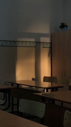 an empty classroom with desks and chairs in front of a wall that has light coming through the window