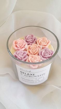 a bowl filled with pink and purple flowers on top of a white sheeted surface