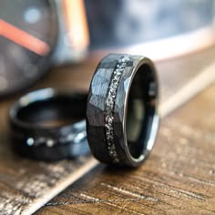 two wedding bands with black and white diamond inlays on top of each other