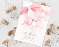 a pink and white wedding card with a bow on it, surrounded by dried flowers