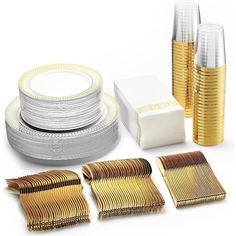 gold and white plates, napkins, and cups are arranged on a white surface